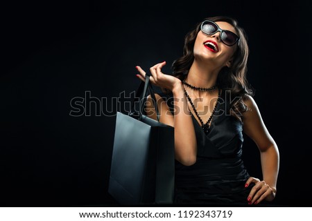 Black friday sale concept. Shopping woman holding grey bag isolated on dark background in holiday Royalty-Free Stock Photo #1192343719