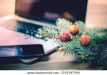 Christmas decoration - fir and shiny balls on an office desk with laptop and cell phone