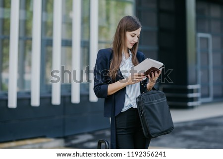 A European-looking girl at the airport with bags and documents is waiting for her flight. Businesswoman in a business suit and with straight hair