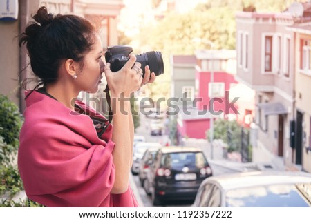 Woman photographer with red scarf, taking pictures of old town