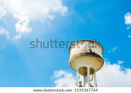 Cement water storage tank with a background of sky and clouds.