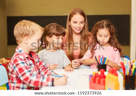 Woman as a teacher and children in art class in preschool or daycare