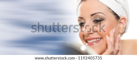 Portrait of smiling young woman applying moisturizing cream on her face
