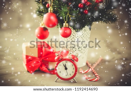 Christmas composition: xmas fir branches, alarm clock, gift box and decorations in the snow atmosphere. Christmas background, greeting postcard. Toned, snow effect.