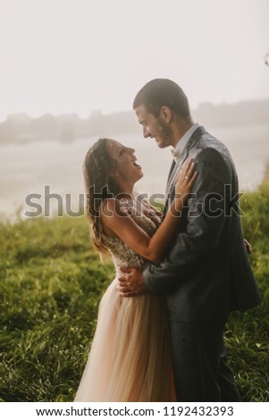 Emotional picture of just married couple standing in field and kissing. River in background.Couple goals.