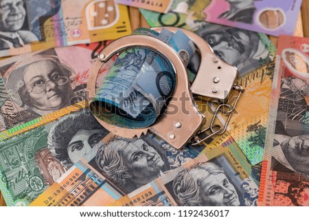 Steel handcuffs on australian dollars background close up