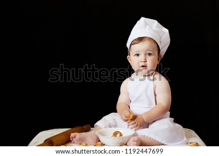 Little beautiful child dressed like a chef on a black background