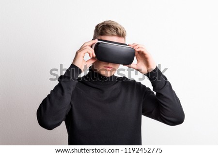 Portrait of a young man with virtual reality goggles in a studio.