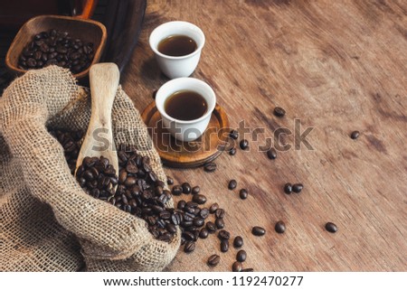 The coffee beans into the cup wood, placed on a wooden floor.