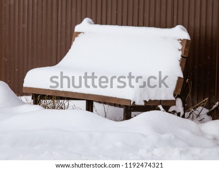 White snow on a bench in the city