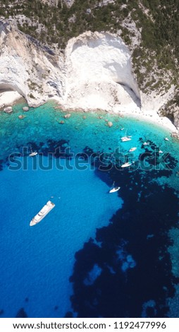 Aerial photo of iconic white cliff tropical bay forming a blue lagoon with deep turquoise clear ocean and docked luxury sail boats and yachts enjoying this unique paradise