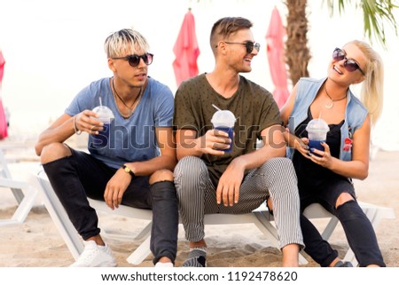 three friends on the beach spend fun while drinking cocktails at sun