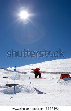 Snowy ski slopes of Pradollano ski resort in the Sierra Nevada mountains in Spain with snowboarder making a jump