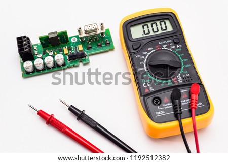 Electric multimeter with red and black probe, display indicating zero, with printed circuit board. Isolated on a white background with a clipping path.