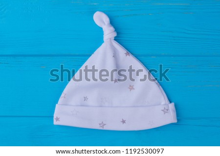 White baby knot hat with printed stars. Blue wood background.