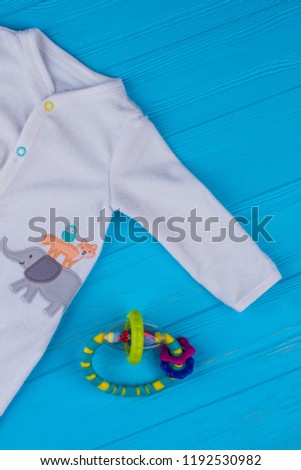 Baby sleepwear outfit and rattle beanbag. Blue wood background.