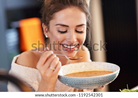 Picture of adult woman tasting pumpkin soup in the kitchen