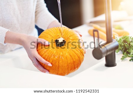 Picture of adult woman washing pumpkin in the kitchen for Halloween