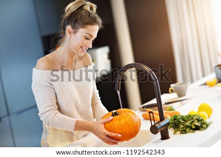 Picture of adult woman washing pumpkin in the kitchen for Halloween