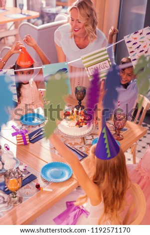 Party for children. Smiling young woman feeling happy while standing next to the table at childrens party