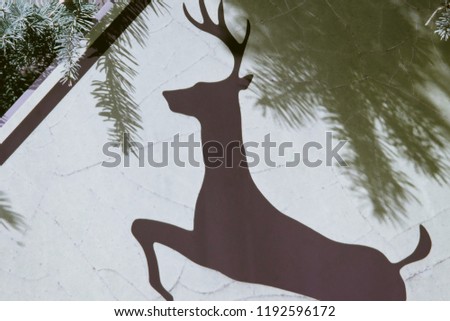 Deer on a roadside sign with pine trees in the background.