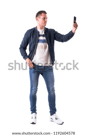 Confident modern handsome man taking self portrait with smart phone. Full body isolated on white background.