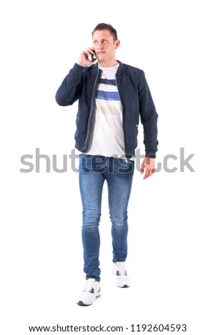 Relaxed young man walking and talking on the cell phone looking up. Full body isolated on white background.