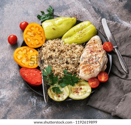Bowl of buddha, chicken grilled, quinoa , tomato, sweet pepper and zucchini on rustic background, top view. Delicious balanced food, concept