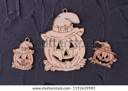 Wooden pumpkin tags on black background. Halloween jack face carved from plywood. Handmade wooden decorations for Halloween.