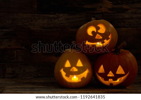Three pumpkin Jack-O-Lantern with happy faces. Carved Halloween pumpkins with burning candles inside. Halloween festive decorations.
