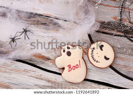 Halloween holiday decorations on wooden background. Decorative web and spiders. Halloween sugar cookies. Halloween holiday theme.