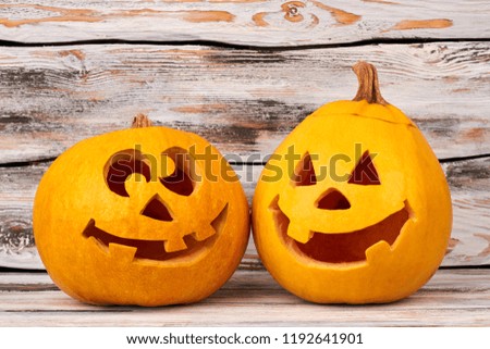 Funny Halloween pumpkins on wooden background. Two smiling Jack-O-Lantern pumpkins. Symbols of Halloween holiday.