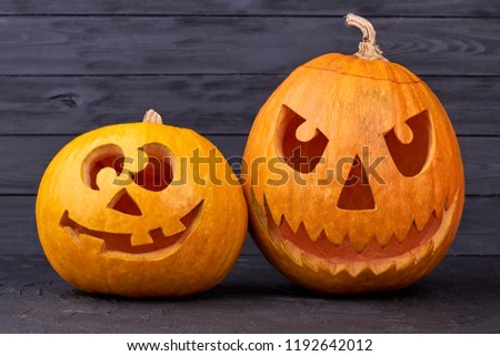 Two Halloween pumpkins on wooden background. Funny and angry pumpkins for Halloween. Cute pumpkin carving ideas.