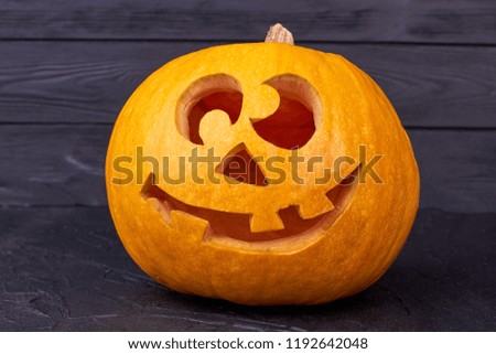 Halloween pumpkin with funny face on black background. Traditional Jack-O-Lantern on dark surface. Symbol of autumn holiday.