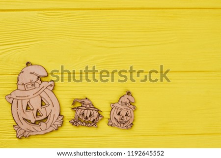 Wooden pumpkin tags on yellow background. Funny pumpkin wooden silhouettes with copy space. Wooden Halloween decorations.