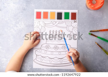 grey background, stationary, children's hands color a picture of birthday cake, flat lay top view. art painting