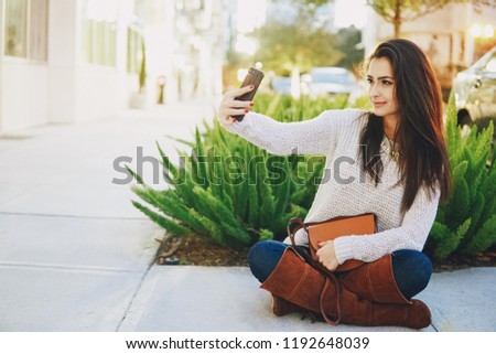 beautiful brunette enjoys phone on the street on a warm evening