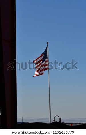 United States flag blowing in the wind with mountains in the background on a hazy day