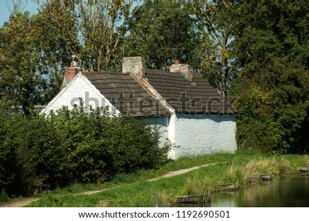 Old white cottage next to a canal
