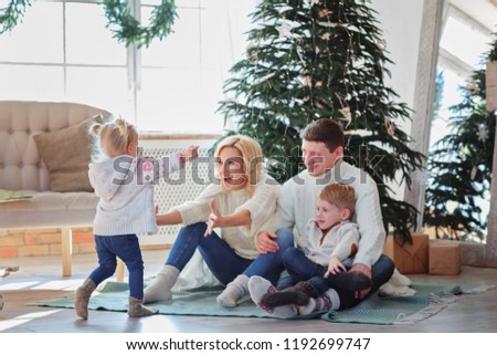 A large happy family sits on the floor near the fireplace and a Christmas tree / a copy of a stretch car