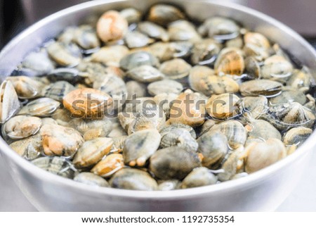 A lot of clams in water in a silver bowl