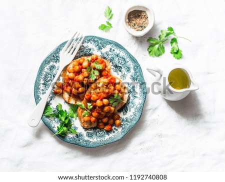 Spicy chickpeas in tomato sauce toast - delicious snack on a light background, top view
