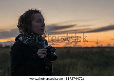 Young lady taking photos of beautiful dusk, using antiques film camera
