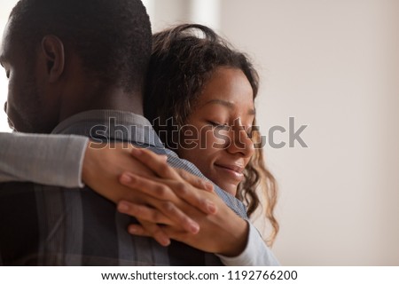 Close up young black american wife embracing husband. Portrait of woman with closed eyes, man rear view. Attractive affectionate couple in love, romantic relationship support and gratefulness concept Royalty-Free Stock Photo #1192766200