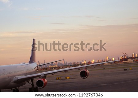 View of an airplane coming to an international airport on background of New York City at sunset.