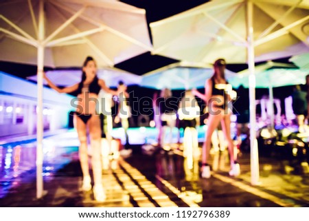 PJ or go-go dance in the rain on a wooden dance floor under an umbrella near the pool. Abstract blurred image