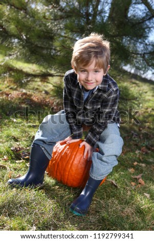 Smiling young boy with a pumpkin in autumn