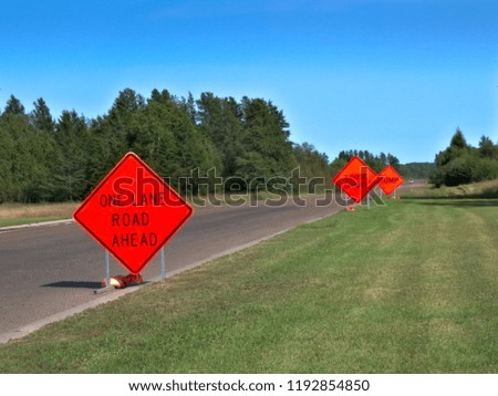 Orange Warning Road Signs on highway at construction site on sunny morning