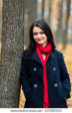Closeup portrait of a young woman in the forest leaning against a tree