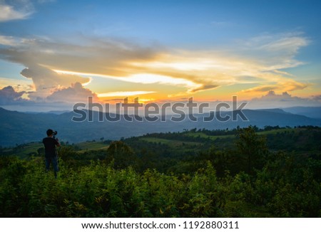 photographer Taking pictures of sunset / beautiful clouds Sunset dramatic colorful of yellow and blue sky on hill with field on mountain landscape